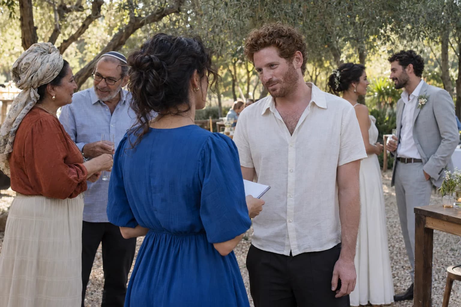 אורחת בשמלה כחולה מול אורח בחולצה בהירה; הזוג ושני אורחים מבוגרים נמצאים לידם